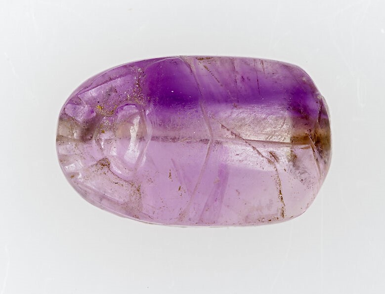 Oval amethyst scarab bead with visible zoning, ca. 664–525 BCE, from ancient Egypt.